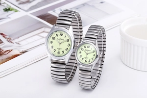 Close-up of silver quartz watches with luminous dials and stretch metal bands