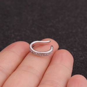 Manchette d'oreille en U argentée avec zircons brillants tenue par les doigts