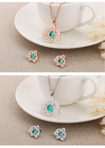 Detail of rose gold and silver jewelry sets with green stones on a white ceramic saucer