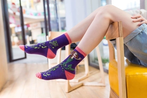 Detailed close-up of purple crew socks with mermaid pattern and pink accents on model