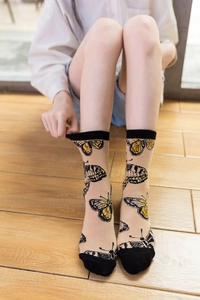 Detailed knit of beige cotton crew socks with black butterfly patterns and toe accents