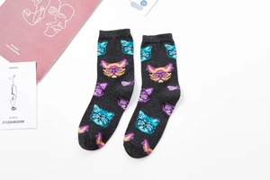 Detail view of dark grey crew socks featuring colorful cartoon cat patterns on a white desk