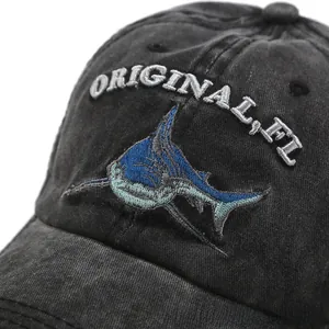 Close-up of shark embroidery and vintage washed denim texture on black baseball cap