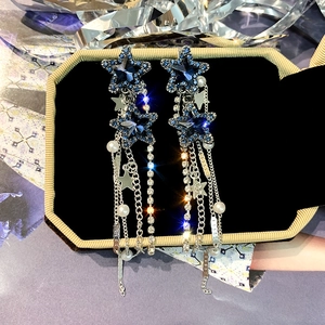 Orecchini lunghi a nappa con strass blu profondo e stelle su vassoio portagioie nero