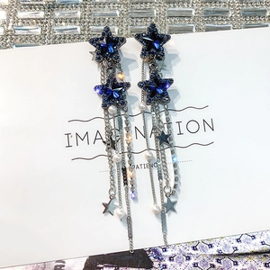Dettaglio macro di orecchini a stella con cristalli blu, nappe d'argento e perle