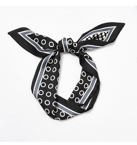 Macro detail of a black silk scarf with white polka dots and gray stripes tied in a bow
