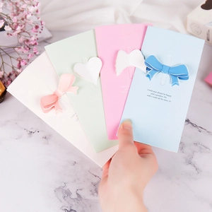 Hand holding four colorful 3D butterfly and heart greeting cards on marble background