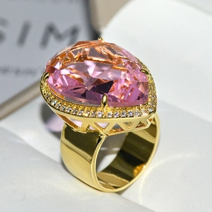 Macro view of luxury teardrop pink crystal ring with gold plating and diamond halo