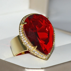 Macro shot of luxury gold ring with large pear-shaped red crystal and white stones