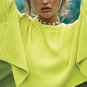 Close-up of vibrant neon green ribbed knit sweater featuring a classic crew neck design