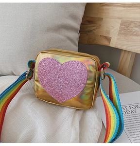 Gros plan d'un sac cœur holographique doré avec bandoulière arc-en-ciel colorée