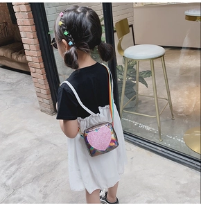 Fille portant un sac à bandoulière en PVC laser avec des paillettes roses devant un café
