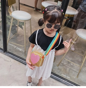 Fillette portant un sac bandoulière cœur doré avec bandoulière arc-en-ciel à paillettes
