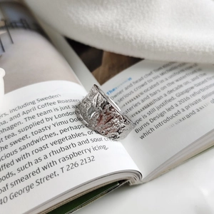 Detail of silver textured wide ring with irregular lava surface on a white magazine