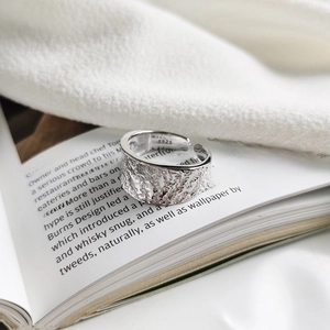 Close-up of S925 sterling silver ring with irregular rock texture on an open book