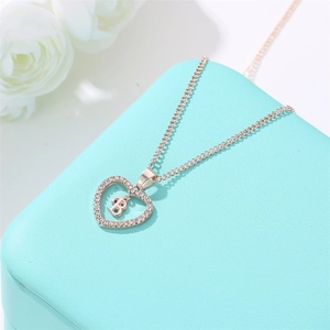 Collier cœur en or rose avec lettre B et cristaux sur un écrin de bijoux