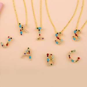 Detailed macro view of colorful zircon-encrusted alphabet pendants on gold chain