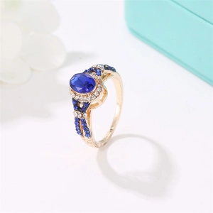 Close-up of vintage gold ring with oval blue zircon and surrounding white diamond accents