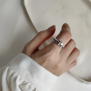 Detail view of a 925 sterling silver T-shaped buckle ring worn by a model in retro style