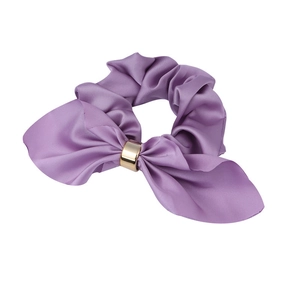 Detail of a purple satin scrunchie with a ribbon bow and a gold metallic ring accent