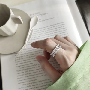 Detailed view of sterling silver ring with rectangular zircons on a hand with coffee