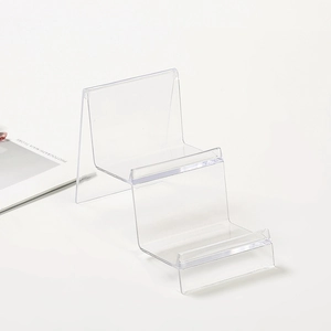 Three-tier transparent acrylic display stand for wallets and phones on a white background