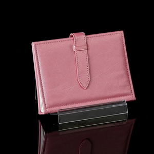 Pink leather wallet displayed on a clear acrylic stand against a black reflective background