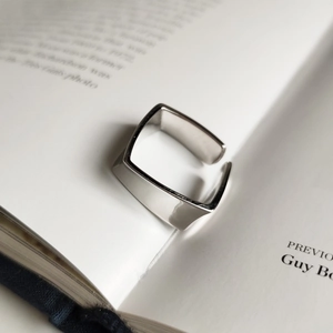 Minimalist square open sterling silver ring on an open book background in clean aesthetic