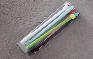 Close-up of four cute cartoon gel pens with silicone toppers in a clear plastic box