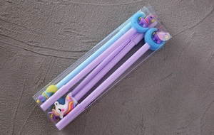 Close-up of pastel cartoon gel pens with silicone unicorn charms in a PVC gift box