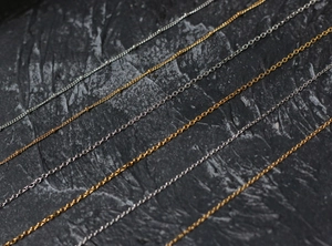 Parallel gold and silver titanium steel chains showing textured weave detail and shine