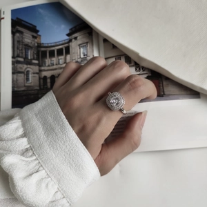 Close-up of 925 sterling silver ring with square zircon on hand over a magazine