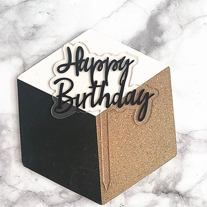 Detail of Happy Birthday acrylic cake topper with gold glitter stem on marble background