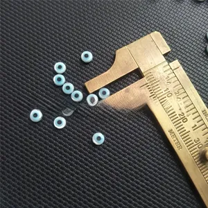 Macro view of 5mm evil eye blue shell beads measured with a brass caliper