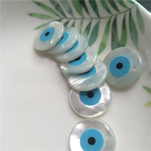 Macro shot of natural mop shell evil eye beads with blue and white iridescent finish