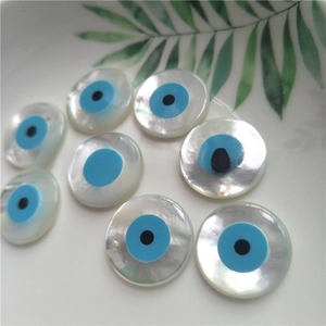 Macro shot of circular natural mother of pearl shell beads featuring blue evil eye designs