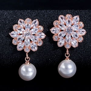 Macro shot of rose gold flower earrings with marquise zircon and pearl drops
