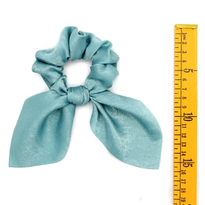 Detail view of light blue satin scrunchie with long rabbit ear bow and measurement tape