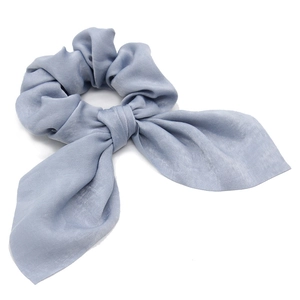 Detailed view of light blue satin scrunchie with elegant bow streamers and silky texture