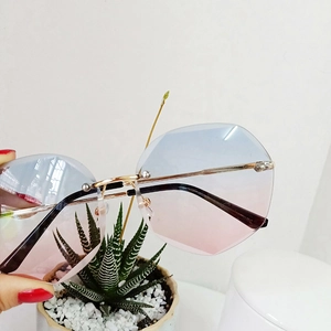 Detail of rimless polygon sunglasses with blue-pink gradient lenses and gold metal temples