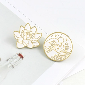 Detail of enamel lotus and Great Wave pins on a magazine, showing golden outlines