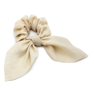 Close-up of cream satin scrunchie with elegant bow detail and smooth silk texture