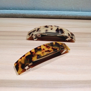 Close-up of dual tortoiseshell arched hair clips with polished finish and metal fasteners