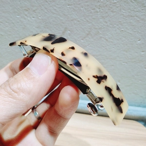 Detailed close-up of tortoise shell pattern hair clip with silver metal spring buckle