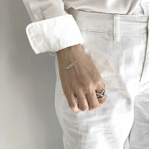 Detailed view of silver minimalist jewelry set with woven ring and slim tag bracelet