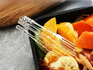Macro shot of ergonomic clear plastic fruit forks on fresh orange and watermelon slices
