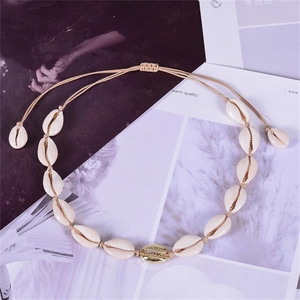 Detail view of handmade cowrie shell necklace with gold accents and adjustable cord