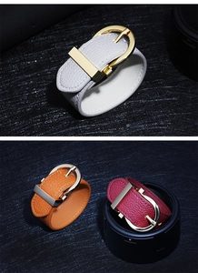 Close-up of three textured leather bracelets in white brown and red with gold metal clasps