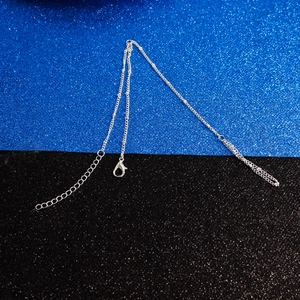 Détail d'une chaîne à billes argentée avec fermoir mousqueton sur fond scintillant