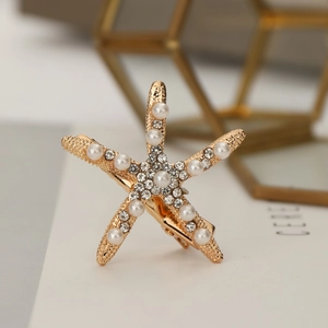 Pince à cheveux étoile de mer dorée avec perles et strass sur fond de luxe chaleureux